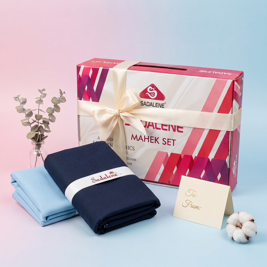 Navy and light blue fabrics beside a pink-and-white Sadalene Mahek Set gift box tied with an ivory ribbon