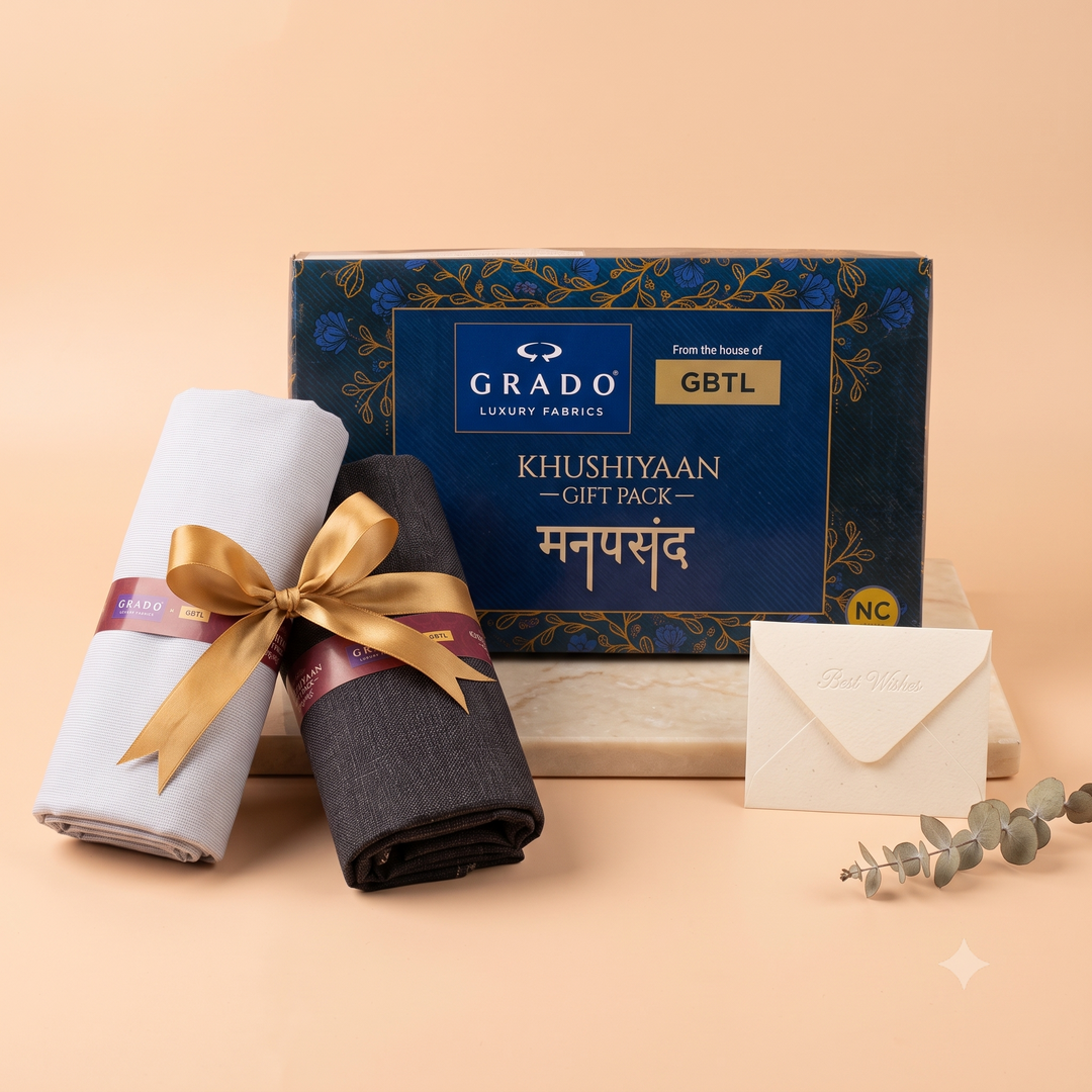 White and charcoal fabrics with a gold ribbon beside a navy GRADO Khushiyaan gift box