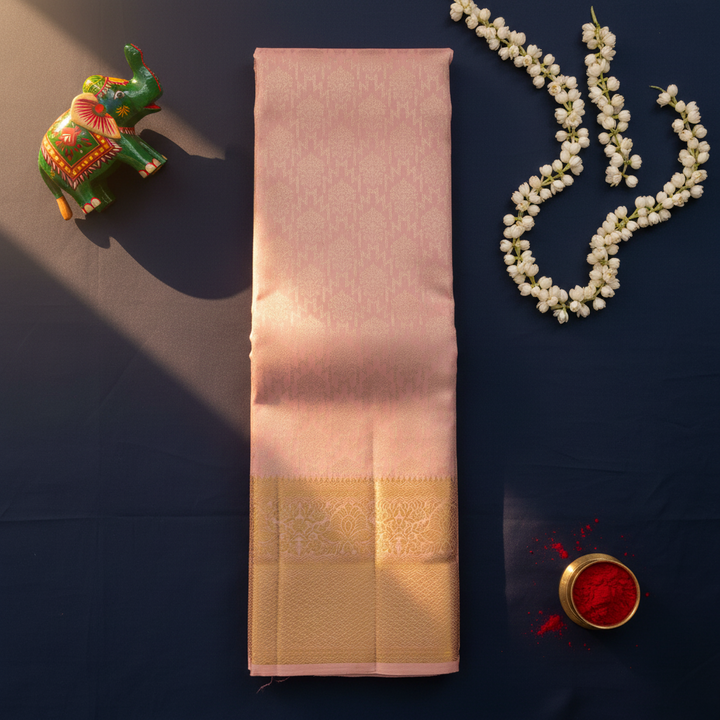 Blush pink Kanchipuram silk saree flat lay with jasmine garland, Channapatna elephant and kumkum