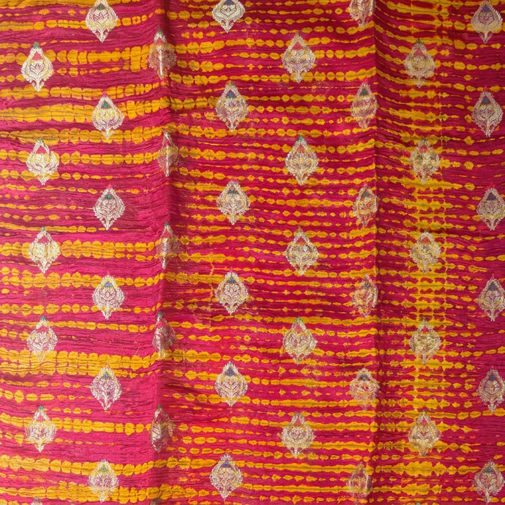 Close-up of yellow horizontal bands and metallic-toned leaf motifs on orange soft-crush fabric