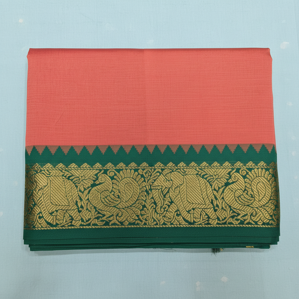 Close-up of peach cotton saree with green contrast border and ornate gold-toned floral motifs