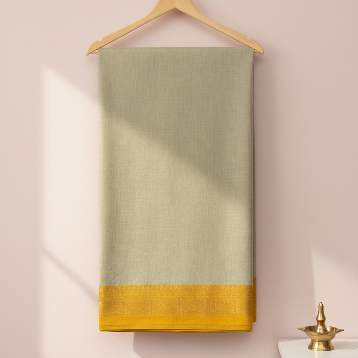 Pista-green cotton saree with a mustard-gold woven border hanging on a wooden hanger against a pastel background with a brass diya
