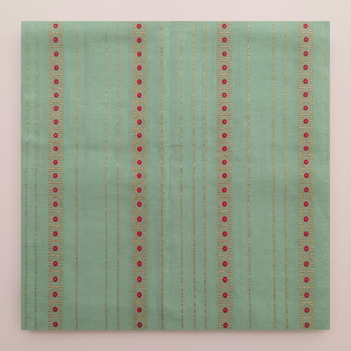 Close-up of the pastel green saree body with vertical rows of small red and gold dots