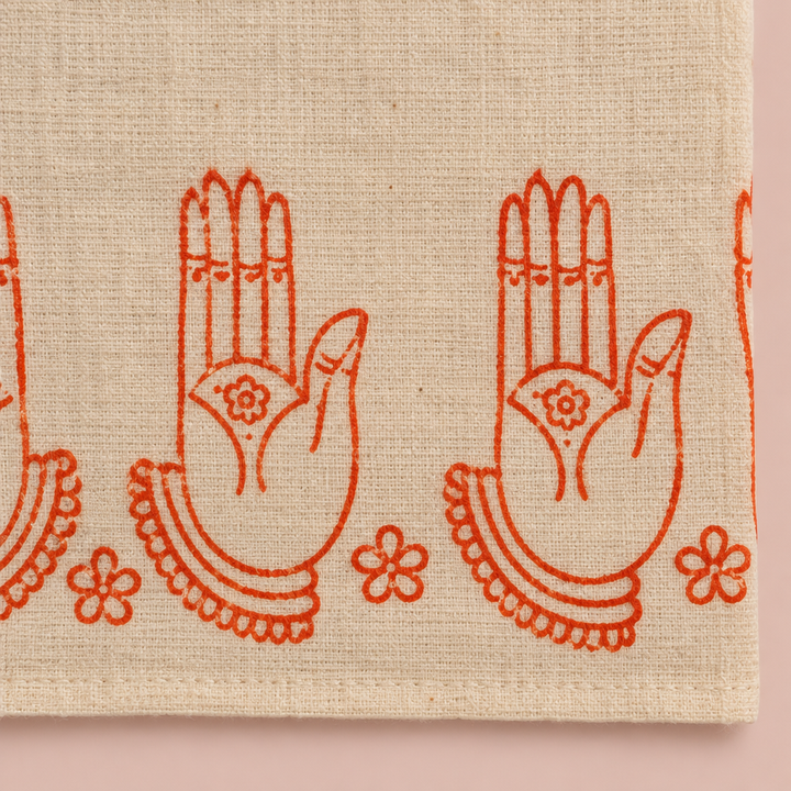 Close-up of orange hand-mudra print border on cream cotton dance saree