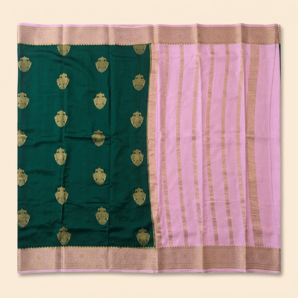 Upstraight overhead view of a dark green pure Mysore crepe silk saree with gold butta motifs, light pink zari-banded contrast section and ornate gold border