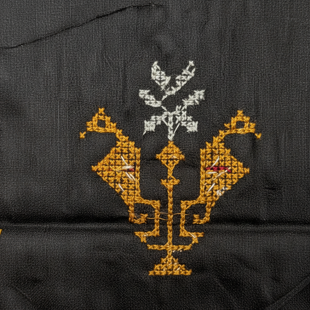 Close-up of gold Kasuti peacock and lamp embroidery on black cotton saree body