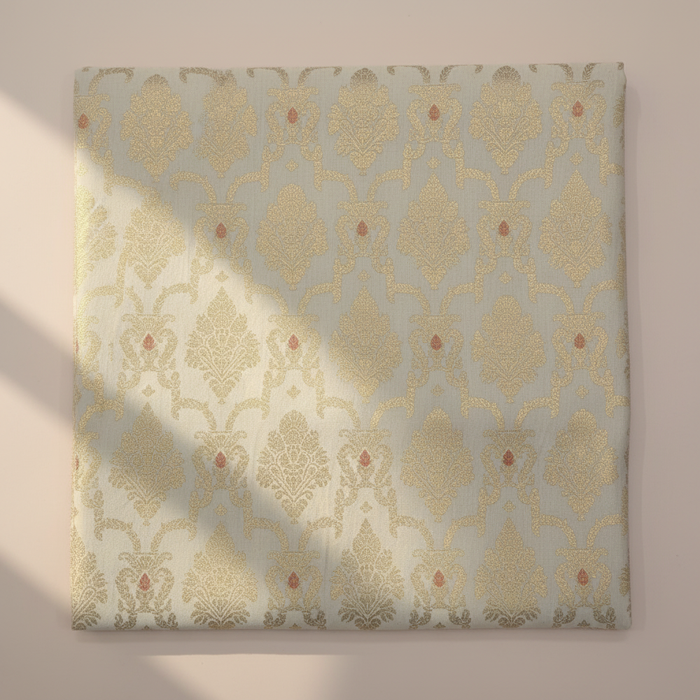 Close-up of cream-gold semi-silk saree with floral zari motifs and red accents