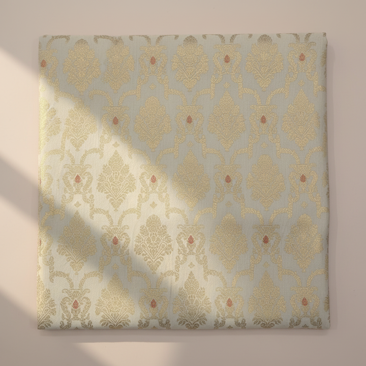 Close-up of cream-gold semi-silk saree with floral zari motifs and red accents