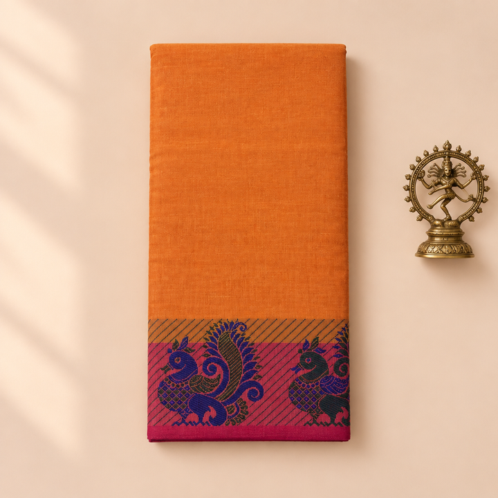 Orange cotton dance saree with magenta peacock border, folded flat lay with Nataraja prop