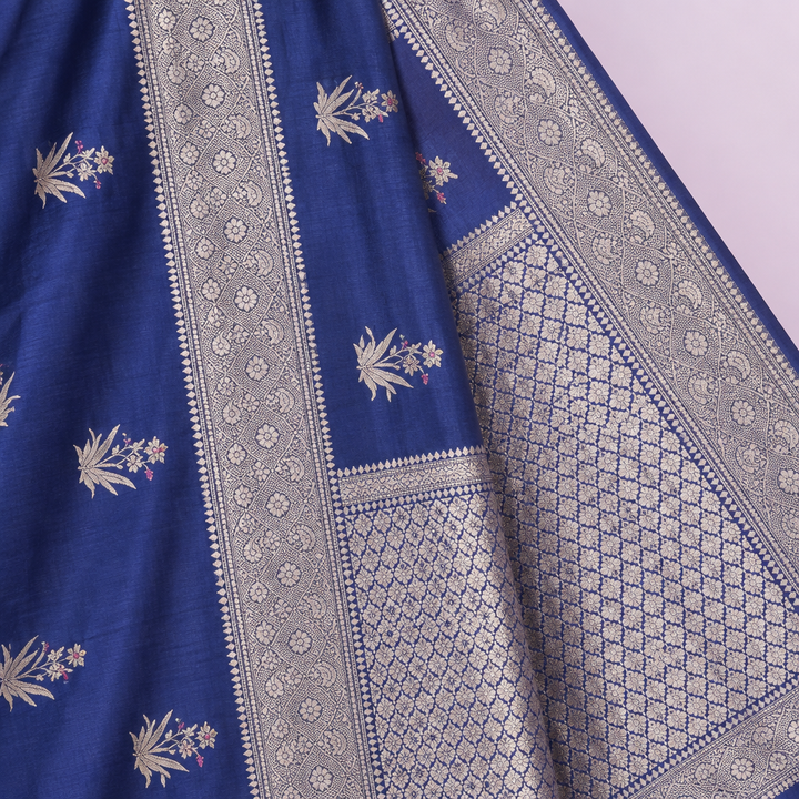 Close-up of the navy blue saree's wide woven silver zari border and patterned pallu