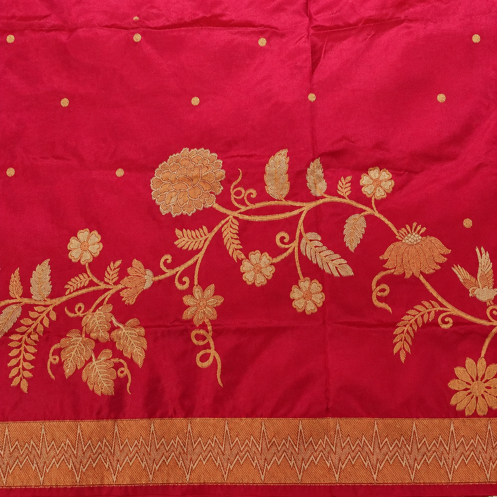 Gold-toned floral vines and scattered dots on pink saree fabric above a zigzag border