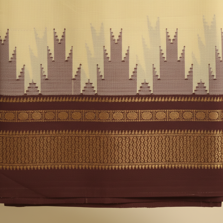 Close-up of the pale-yellow saree with its mauve, taupe, and grey jagged motif band and chocolate-brown border with antique-gold detailing