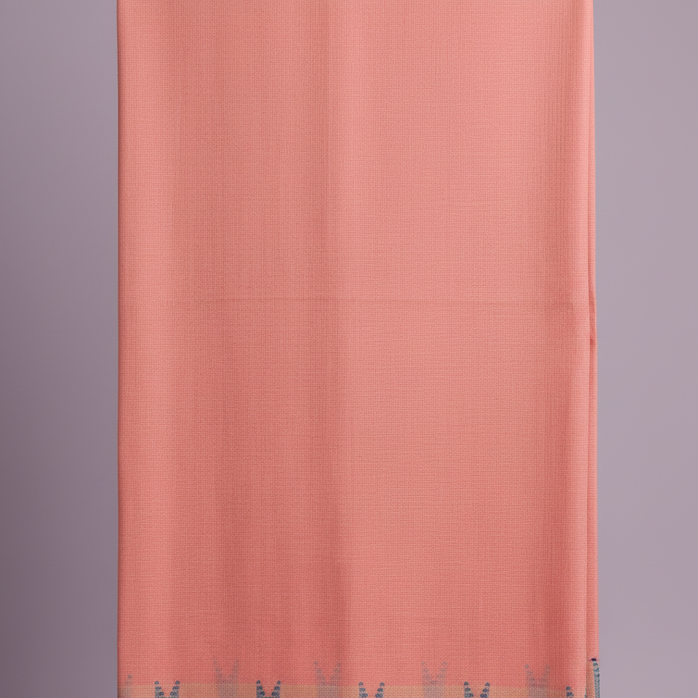 Close-up of the soft coral-peach pink cotton saree body showing its subtle tonal weave and texture