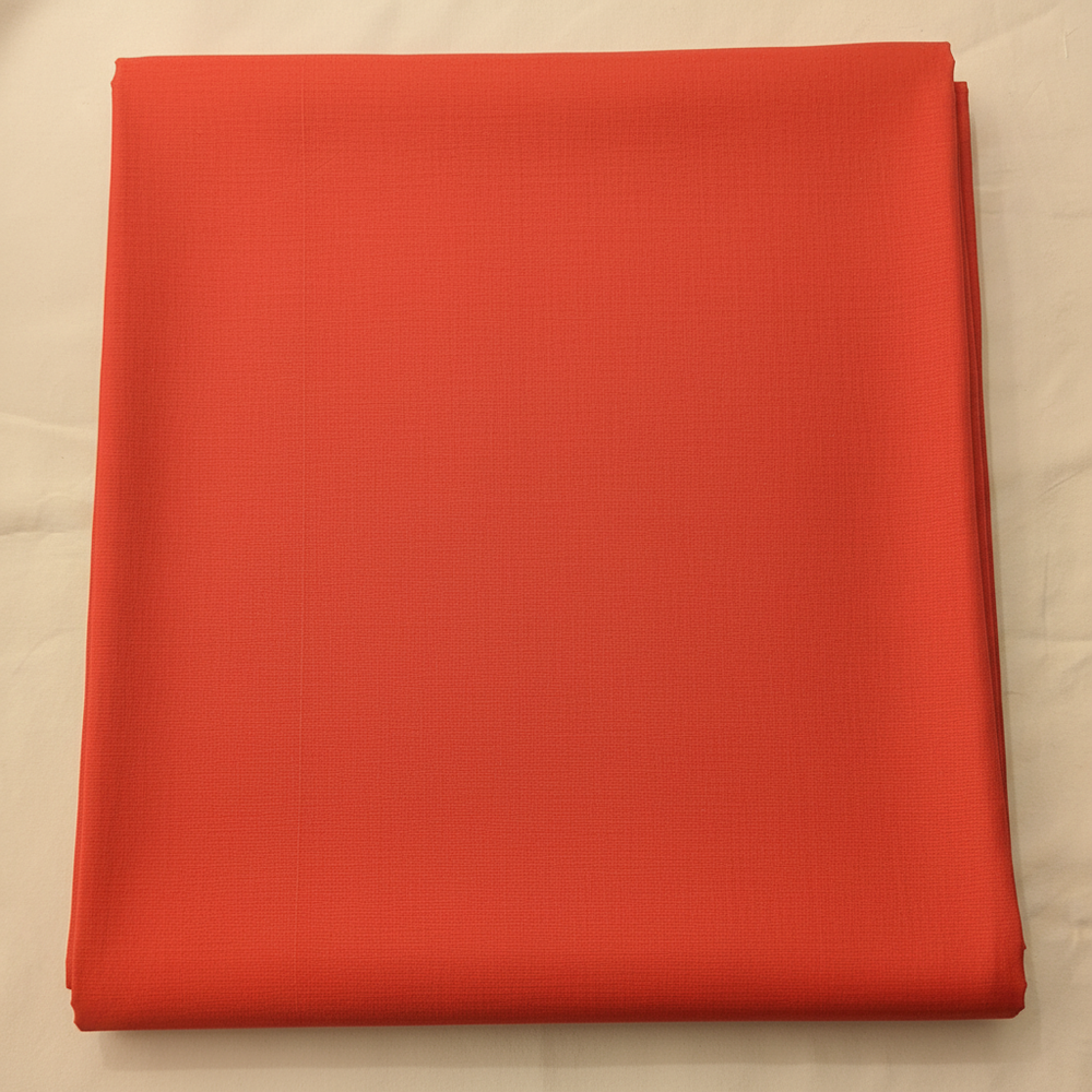 Close-up of the peach-coral cotton saree showing its warm vermilion body and subtle woven texture