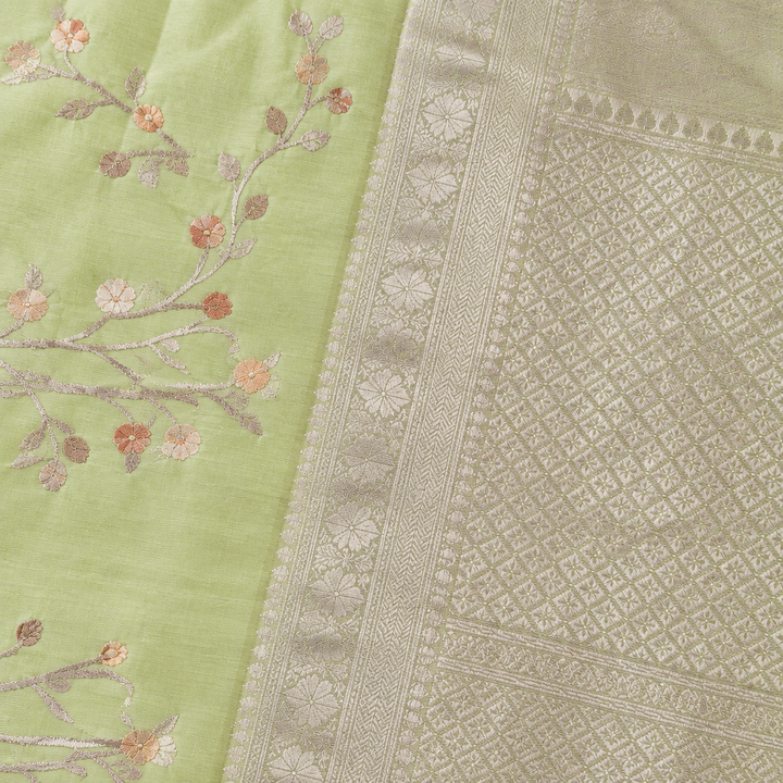 Close-up of the parrot green saree's wide silver zari border and patterned pallu