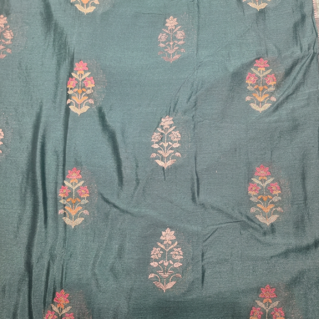 Close-up of pink and pale metallic floral plant motifs on blue saree body