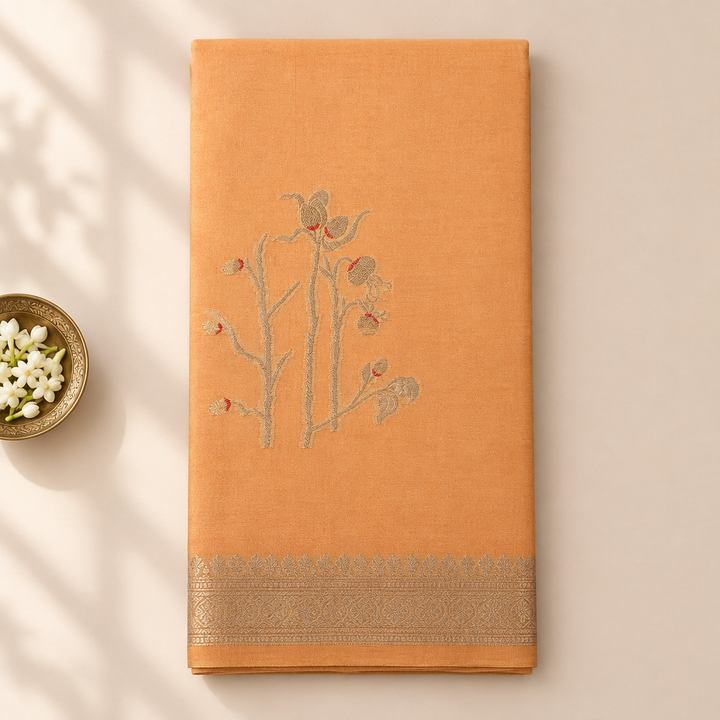 Kuberan peach-orange pure Tussar silk saree folded upright on a pastel background with a jasmine bowl