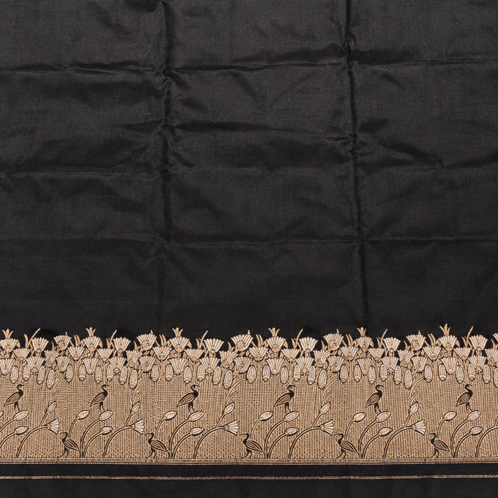 Plain black saree body above pale gold-toned botanical vines and floral border detailing