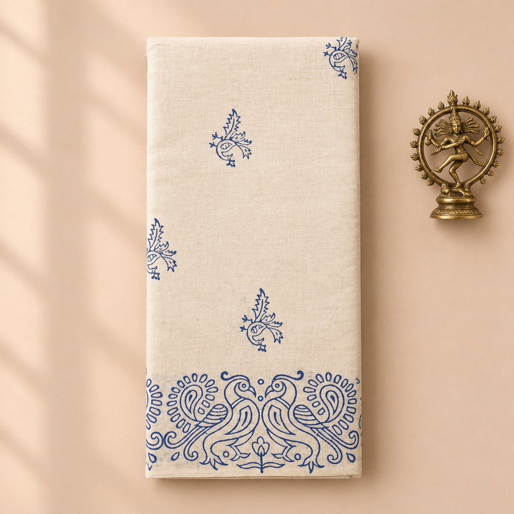 Cream cotton dance saree with blue peacock print border, folded flat lay with Nataraja prop