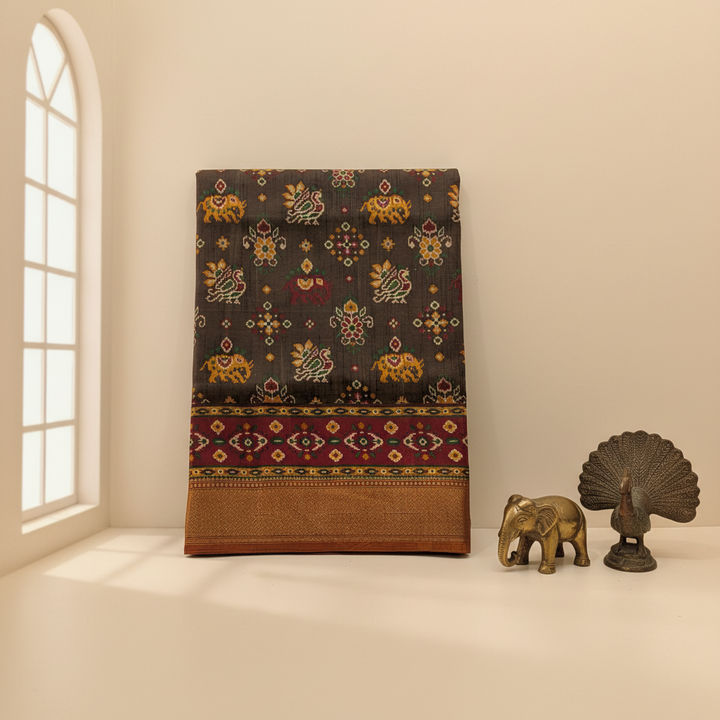 Patola silk saree styled with warm ivory pastel background, antique brass props, and natural window light