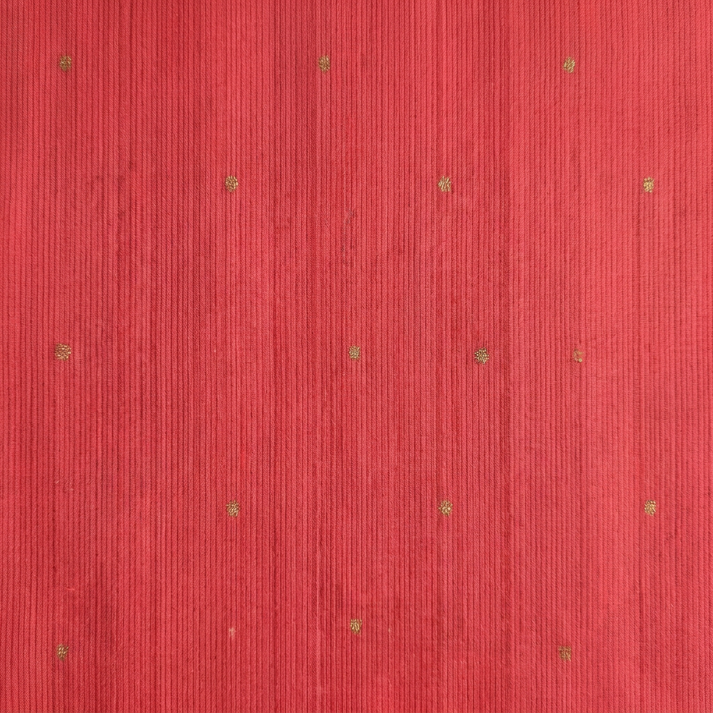 Close-up of the coral red saree body with subtle gold butta motifs and fine vertical woven texture