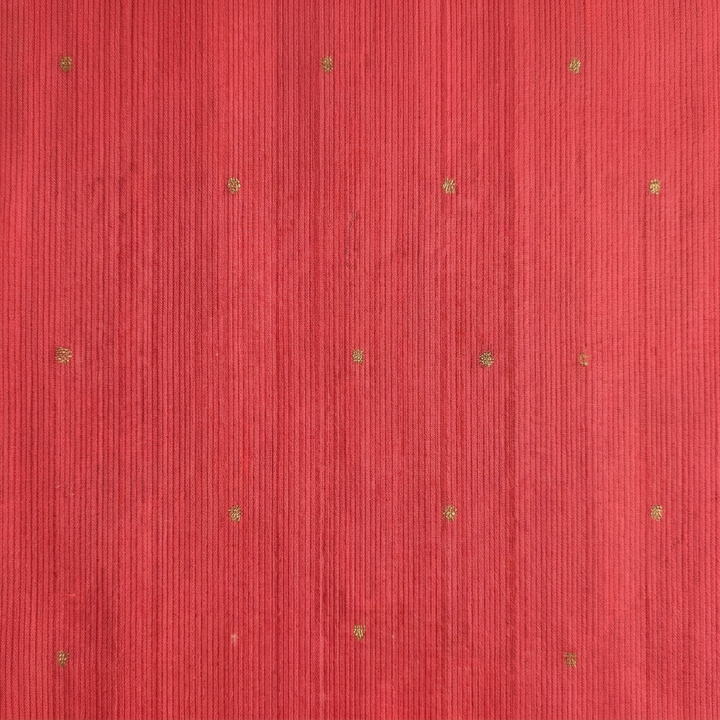 Close-up of the coral red saree body with subtle gold butta motifs and fine vertical woven texture