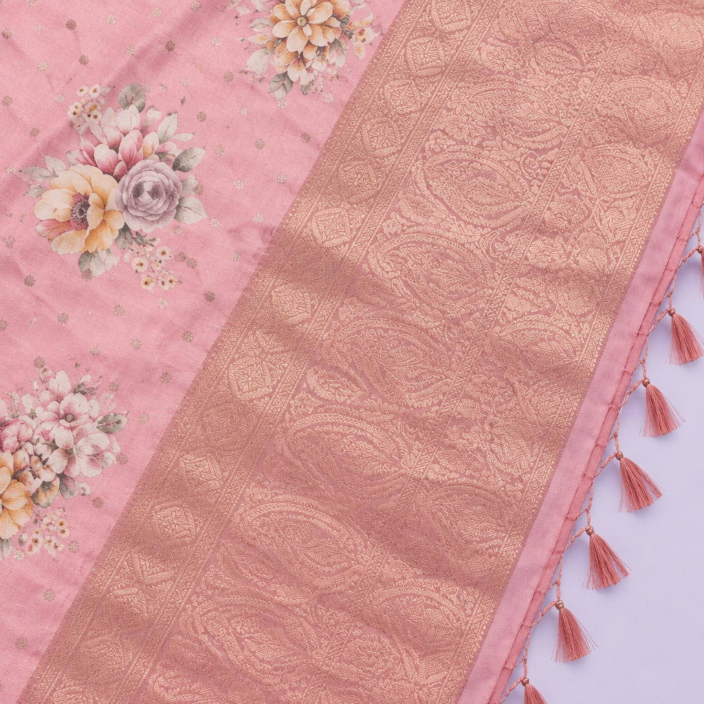 Close-up of the peach saree's wide rose-gold woven zari border and tasselled pallu