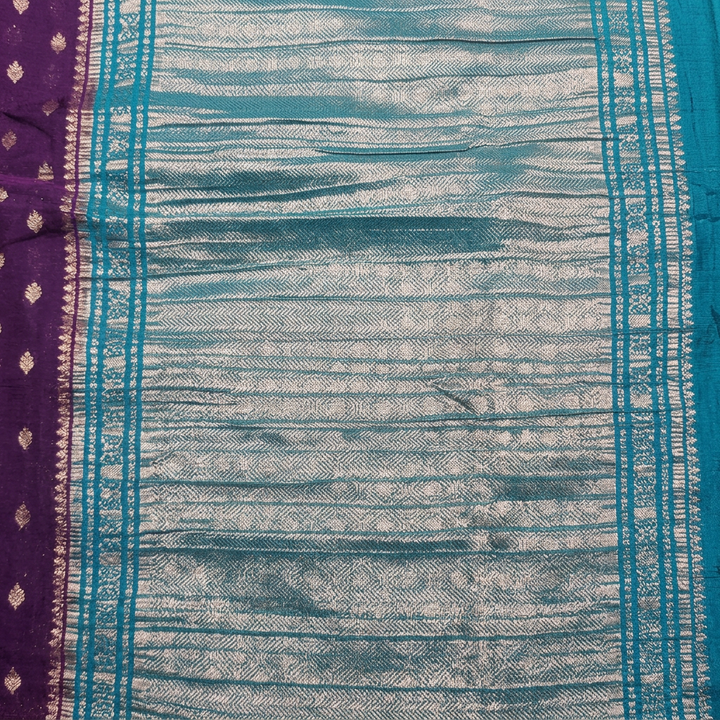 Close-up of silver-toned patterned pallu with turquoise-blue stripes beside purple motif body
