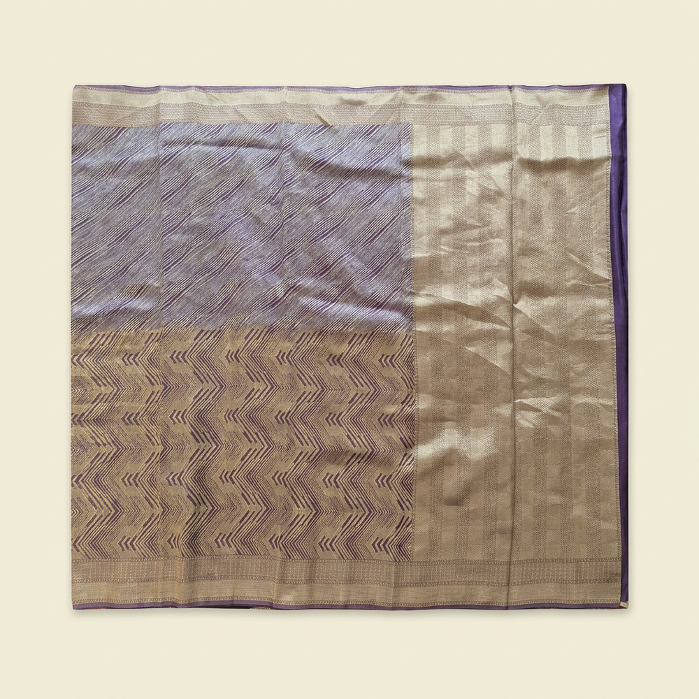 Straight overhead view of purple saree with gold-toned chevron design and broad pallu