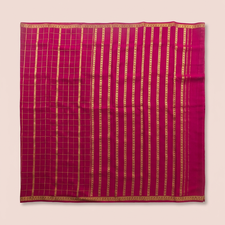 Upstraight overhead view of a pink pure Mysore crepe silk saree with a gold zari checked grid section, dense vertical gold zari bands and ornate gold border