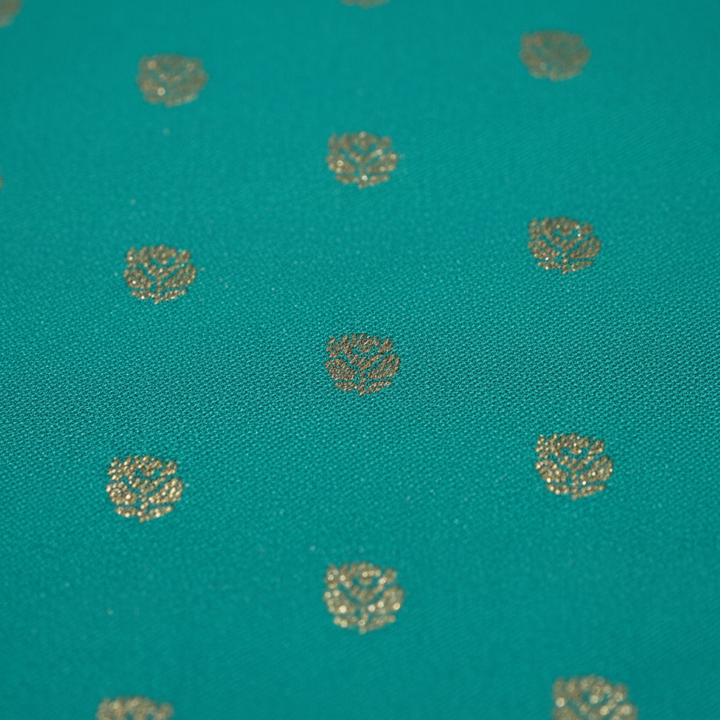 Close-up of golden zari buti motifs on teal saree body