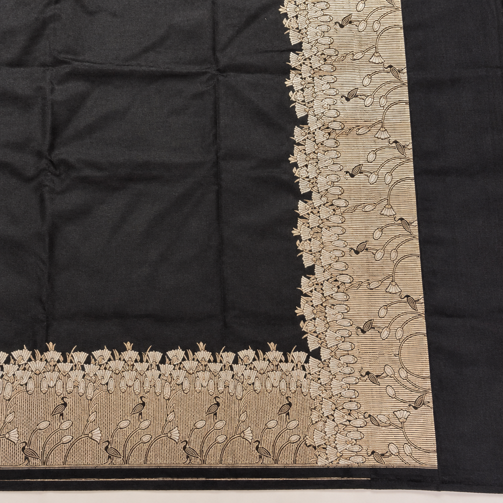 Corner detail of matching pale gold-toned botanical borders against black saree fabric