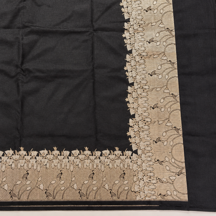 Corner detail of matching pale gold-toned botanical borders against black saree fabric