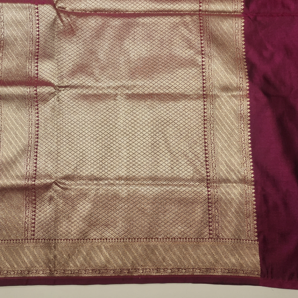 Close-up of gold-toned diamond-lattice pallu and patterned border on burgundy semi Banarasi saree
