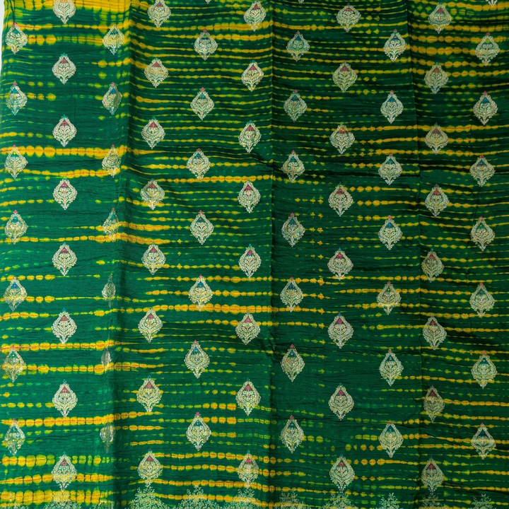 Close-up of green silk with irregular yellow bands and metallic-toned leaf motifs