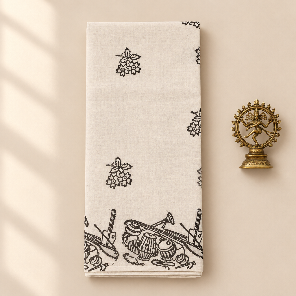 Cream cotton dance saree with black musical instrument print border, folded flat lay with Nataraja prop