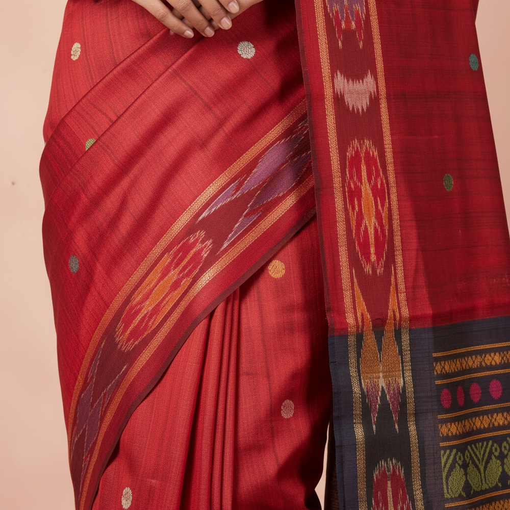 Close-up of the red Tussar silk saree body showing its scattered multicolour motifs and subtle sheen