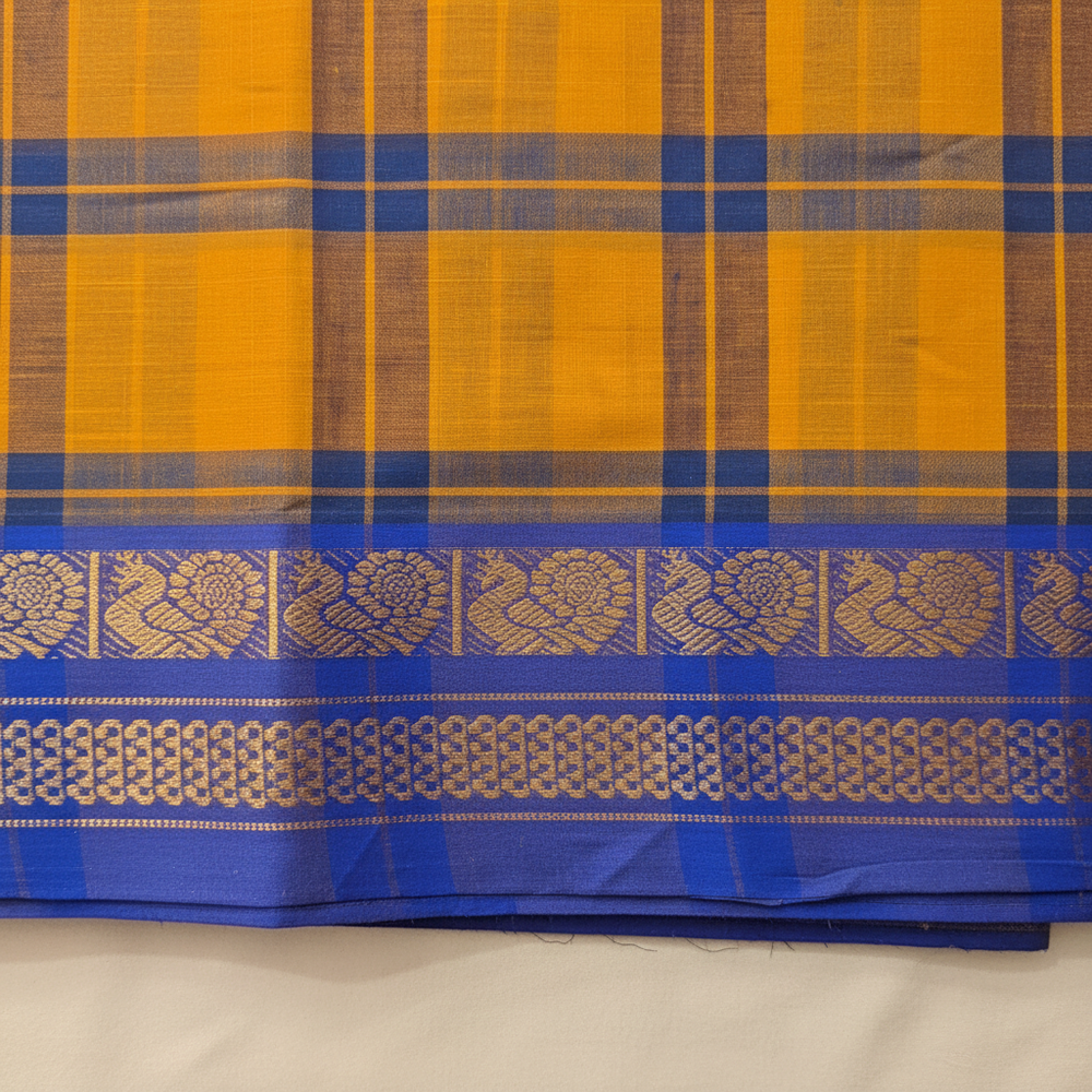 Close-up of the mustard-yellow checked saree showing its navy border bands, antique-gold floral motifs, and rich royal-blue edge