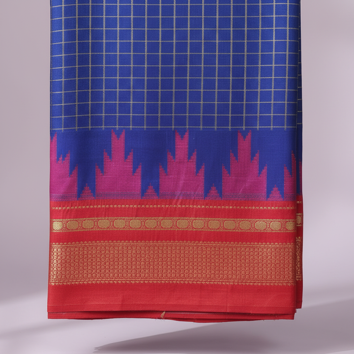 Close-up of the royal-blue saree with its magenta and pink jagged motif band and vivid red-coral border with gold and orange geometric detailing