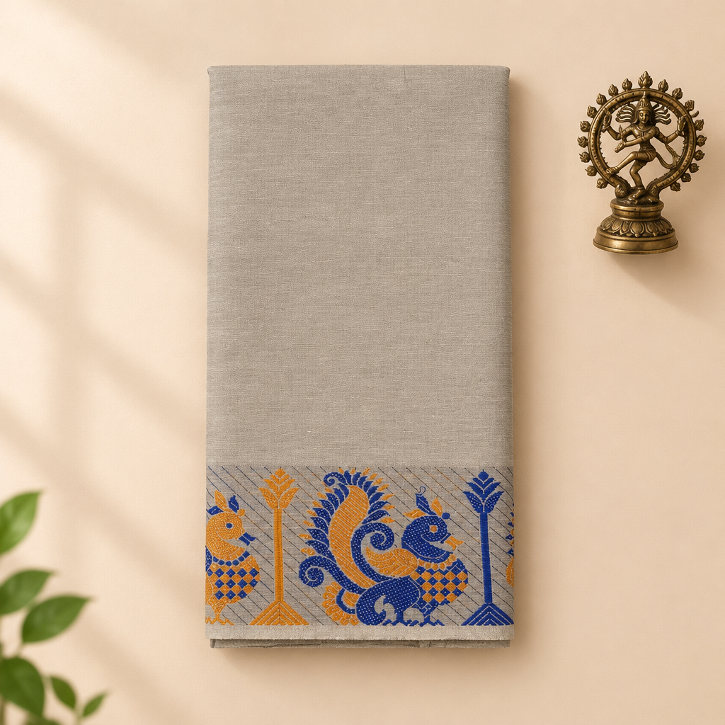 Light grey cotton dance saree with blue and orange peacock border, folded flat lay with Nataraja prop