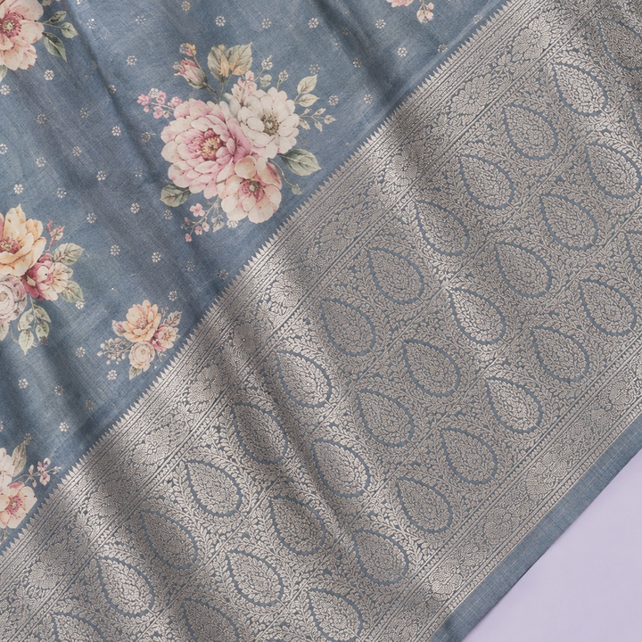Close-up of the grey-blue saree's wide woven silver zari border and patterned pallu
