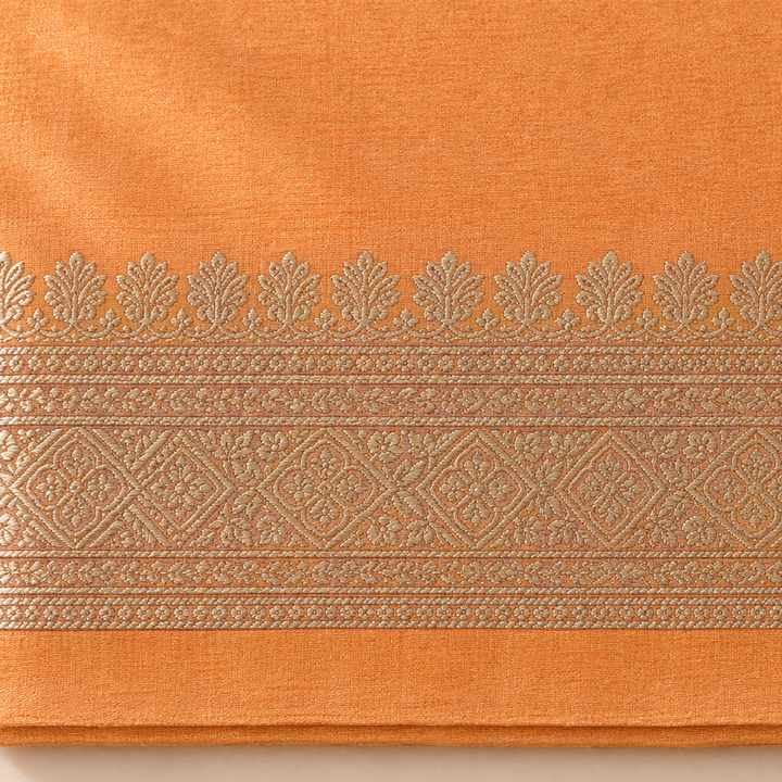 Close-up of the peach-orange saree's woven silver zari border