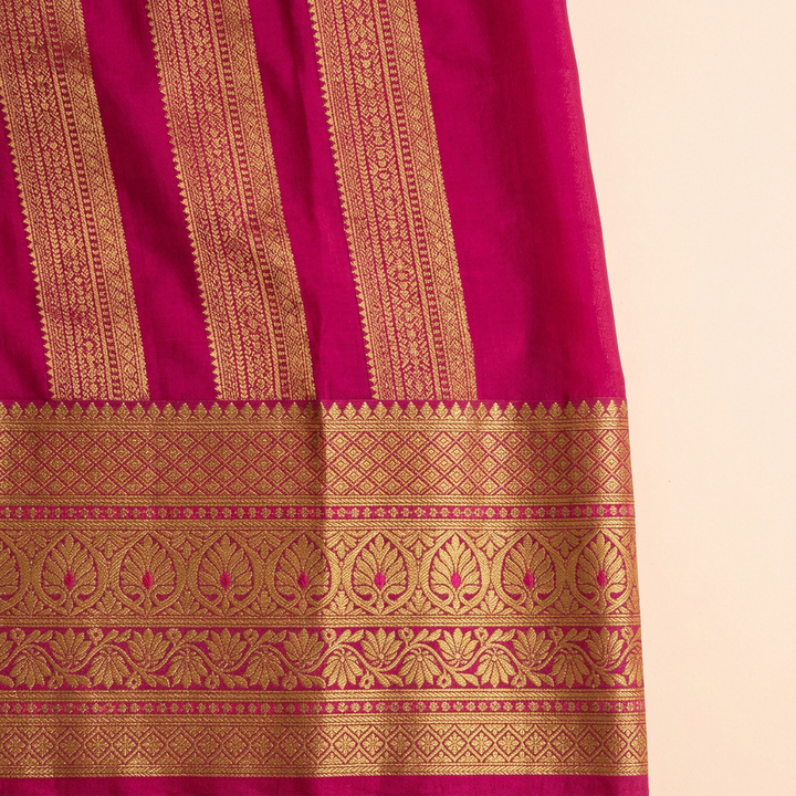 Close-up of the magenta-pink contrast section with dense gold zari woven bands and ornate gold border