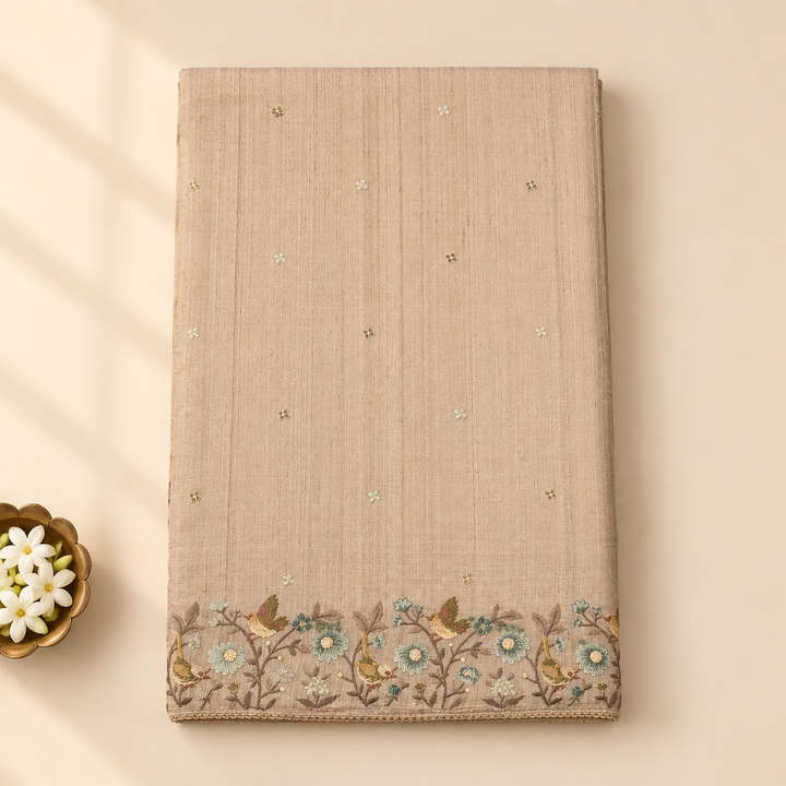 Kuberan beige pure Tussar silk saree folded upright on a pastel background with jasmine buds