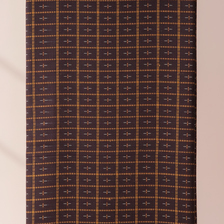 Close-up of the brown, aubergine, and plum cotton saree with a fine mustard-gold and orange checked weave and small light woven cross motifs